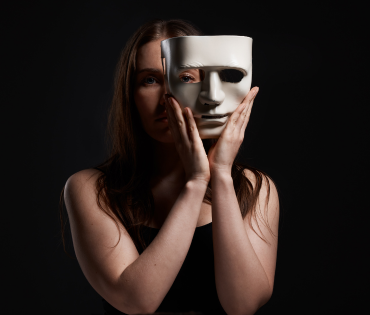 woman holding a white mask infront of her face